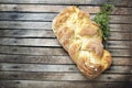 Top shot, close up of fresh baked homemade vegan braided loaf on a wooden, rustic table background, branches of thyme, home baking