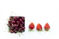 Top shot, close up of fresh sweet cherries with water drops in white bowl and strawberries isolated on white background, selective Royalty Free Stock Photo