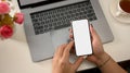 Top shot, Female hands using smartphone over laptop on white background Royalty Free Stock Photo