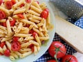 Top shot of a plate full of Italian pasta with sliced cherry tomatoes and spices