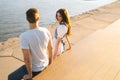 Top side view of young attractive woman flirting with man sitting on bench on city waterfront near river in sunny summer Royalty Free Stock Photo