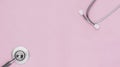Top table view or flat lay of stethoscope on pink paper background by eartips and bell diaphragm located in each corner of frame Royalty Free Stock Photo
