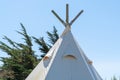 Top of teepee tent against a clear blue sky