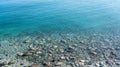 Top up view of multicolored pebble and average size stones at sandy bottom of sea beach under clear water in Norway, close to