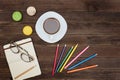 Top viev on a coffee mug, macaroons, colored pencils and a notebook. Wooden background Royalty Free Stock Photo