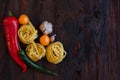 Top viev Italian raw nest pasta with vegetables tomatoes, chili peppers, garlic, spices on a dark wooden background Royalty Free Stock Photo