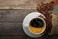 Top view above of Black hot fresh coffee with smoke and milk foam in a white ceramic cup with coffee beans roasted in burlap sack Royalty Free Stock Photo