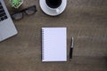 Top view above of Notebook on wooden office desk table with laptop and coffee cup with equipment other office supplies. Royalty Free Stock Photo