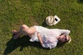 Top view from above of a woman lying and relaxing on a meadow covered with green grass on a sunny summer or spring day. Royalty Free Stock Photo