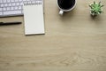 Top view above of Wooden office desk table with keyboard, notebook and coffee cup with equipment other office supplies. Royalty Free Stock Photo