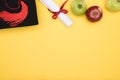 Top view of academic cap, diploma and apples on yellow surface. Royalty Free Stock Photo