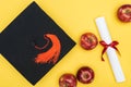 Top view of academic cap, diploma and apples on yellow surface. Royalty Free Stock Photo