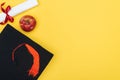 Top view of academic cap, diploma and red apple on yellow surface. Royalty Free Stock Photo