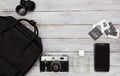 Top view accessories -backpack, vintage camera,mobile phone,retro slides ,lens and parfume on white wooden background.Black and