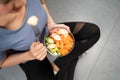 Top view of active woman sitting and eating cut red and green apple mixed with carrot in glass bowl picking with a fork. Royalty Free Stock Photo