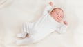 Top view on adorable newborn baby in white bodysuit lying on bed and looking on bright sun. Newborn babies at home Royalty Free Stock Photo