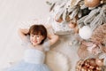 top view of adorable smiling little girl in princess blue dress lying on gift boxes near festive decorated with pink