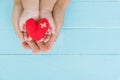 Top view of adult and child holding red heart in hands