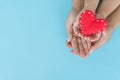 Top view of adult and child holding red heart in hands