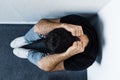 View of adult depressed man sitting on floor in corner and holding hands on head Royalty Free Stock Photo