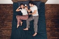 Top view. Adult handsome man with alarm clock woke up young woman lying on bed. Royalty Free Stock Photo