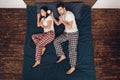 Top view. Adult handsome man plans to wake up with alarm clock sleeping young woman lying on bed. Royalty Free Stock Photo