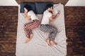 Top view. Adult handsome man looks at phone screen next to sleeping woman on couch.