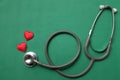 Image of a top view stethoscope and red heart on a green background, concept of health and medicine.