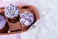 Top view of aesthetics purple floral cupcakes with cup of coffee. No sugar dessert among lilac flowers