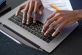 Top view of african man hands typing on the laptop, contract on desk