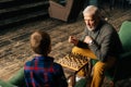 Top view of aged-male grandfather playing chess with grandson sitting at desk in cozy living room