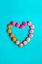 Top view Allsorts chocolate Sweets with multicolored cream filling arranged in heart shape on light blue background. Happy