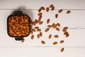 Top view of almonds on dark stone table with wood spoon or scoop. Almond in wooden bowl. Nuts freely laid on dark board.