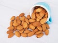 Pour almonds seeds from blue cup isolated in white table Royalty Free Stock Photo