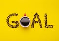 Top view Americano in red cup and coffee beans spell for word GOAL on yellow Royalty Free Stock Photo