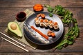Top view of appetizing Japanese sushi rolls in big black plate, serving with fish slices, sauces, caviar, avocado, salad Royalty Free Stock Photo