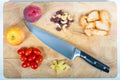 Top view of an apple, a peach, tomatoes, pieces of pineapple, chicken, raisins and peanuts with a knife