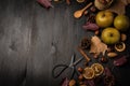 Top view of apples, nuts, oranges, cinnamon, scissors and autumn leaves, on a dark wooden background,