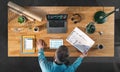 Top view of architect working on computer at desk with paperwork in home office, video call concept. Royalty Free Stock Photo