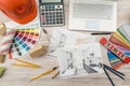 Top view of architects drawing modern house with sample material, hardhat, laptop on creative table