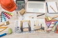 Top view of architects drawing modern house with sample material, hardhat, laptop on creative table