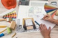 Top view of architects drawing modern house with sample material, hardhat, laptop on creative table