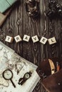 top view of arranged wooden blocks in travel word with map, retro photo camera, bag and magnifying glass on dark Royalty Free Stock Photo