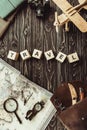 top view of arranged wooden blocks in travel word with map, retro photo camera, bag and magnifying glass on dark wooden tabletop Royalty Free Stock Photo