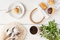 Top view of arrangement of assorted mini cakes on plate and tray, cup of coffee and green leaves on white background Royalty Free Stock Photo