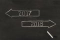top view of arrows with 2017, 2018 year signs and piece of chalk on dark