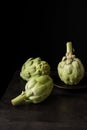 Top view of artichokes on black plate on wooden table, with selective focus, black background Royalty Free Stock Photo