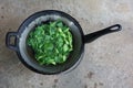 Top view of Asian food green leaf kale simmering in an old rustic pan.