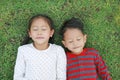 Top view Asian little child boy and girl lying on green grass outdoors in summer park. Portrait of sister and brother closed eyes Royalty Free Stock Photo