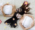 Top view for 2 asian women sleep on white carpet and her are long black hair, face has masked with herb cream and dress a white Royalty Free Stock Photo